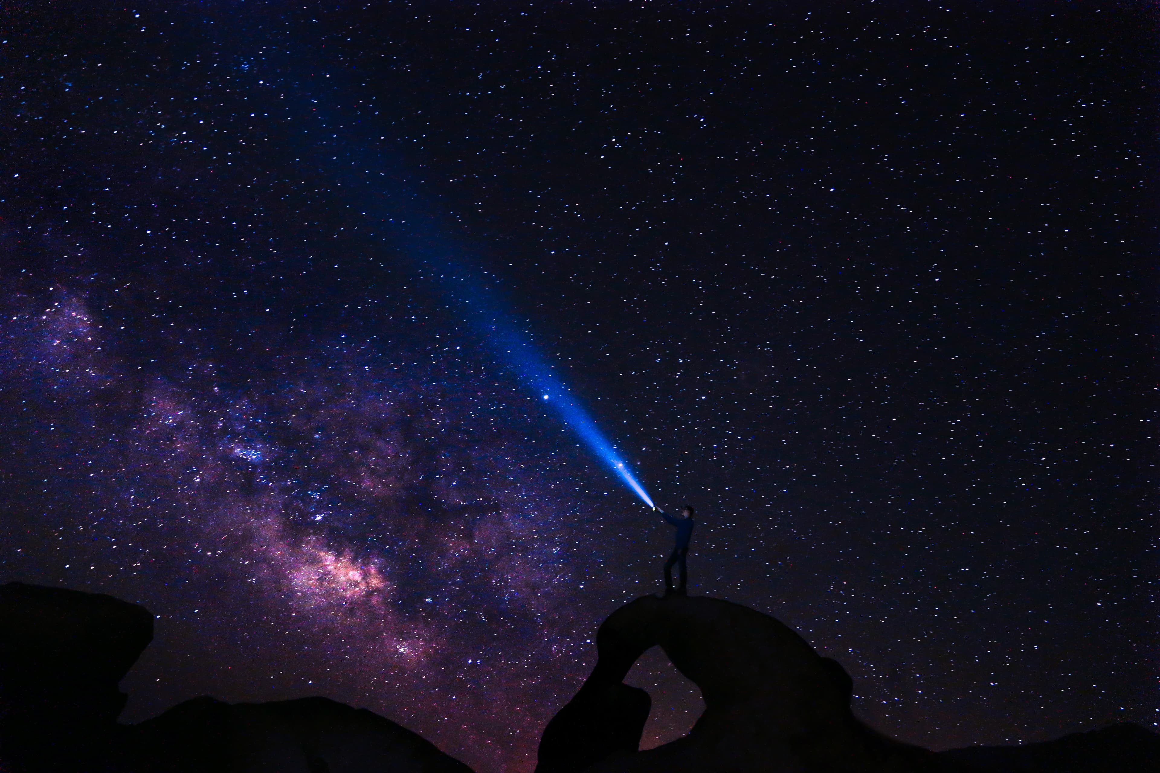 Person shining a light into the stars and milky way